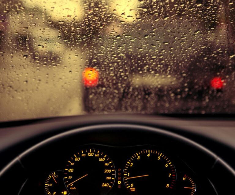 a close up of a dashboard with a view of a street through a rain covered window