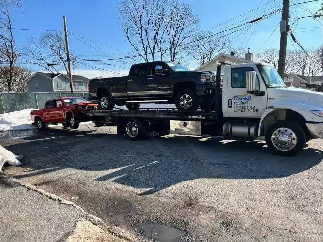 there is a truck that is towing a red truck in the street