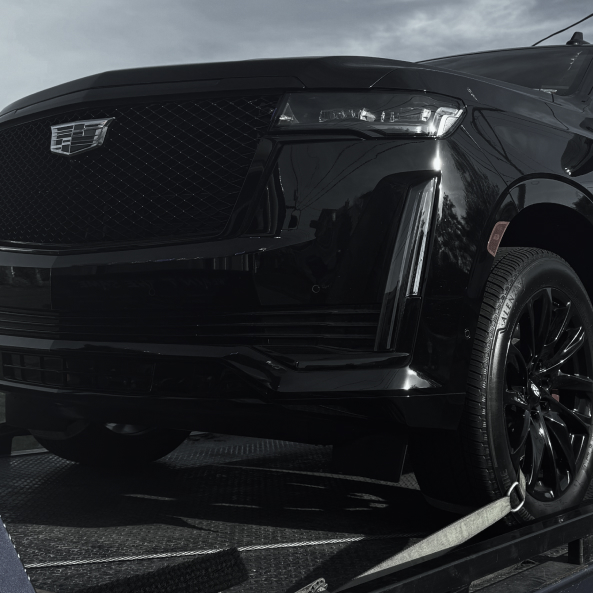 a close up of a black car on a flatbed trailer