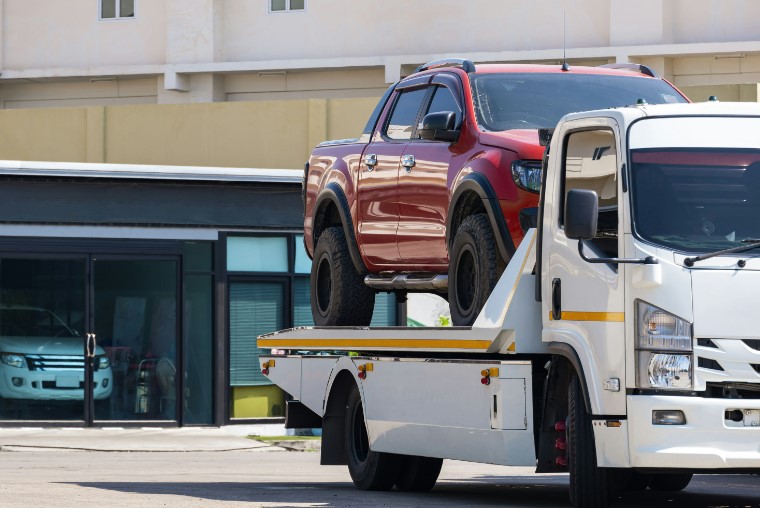 arafed truck on a flatbed tow truck with a red truck on top