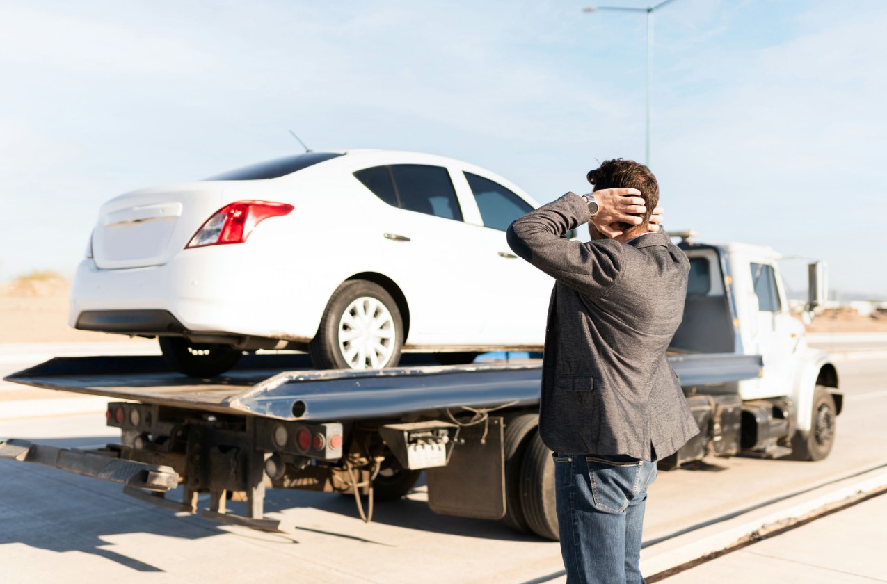 arafed man taking a picture of a white car on a flatbed